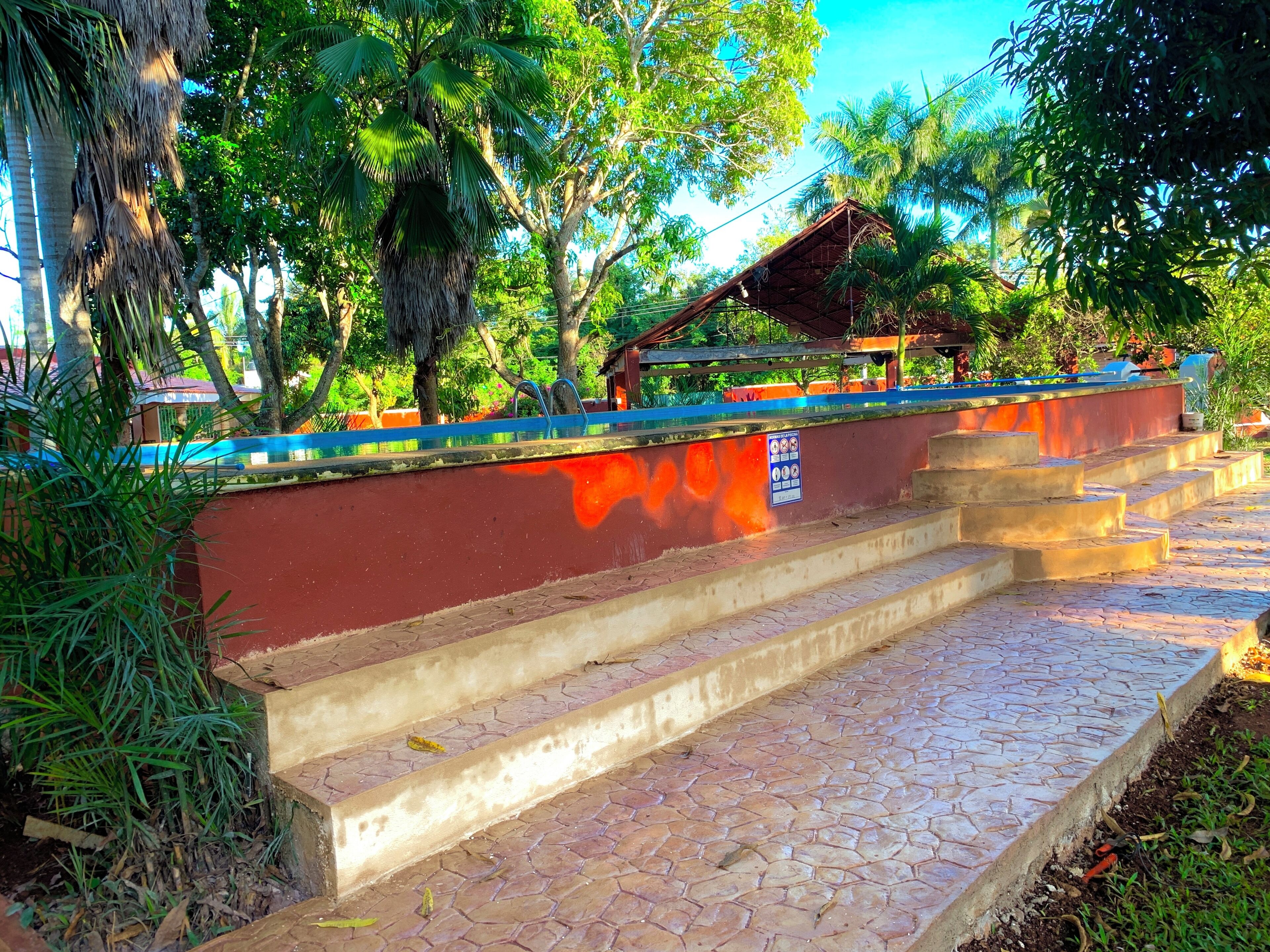 Una escalera que sube a un espacio cubierto con una pared roja y una barandilla azul.