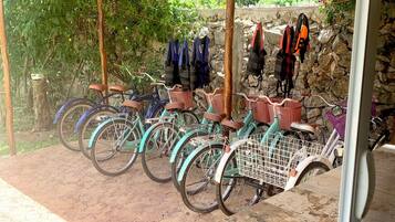 Un espacio al aire libre techado con bicicletas estacionadas bajo un refugio, un muro de piedra y un piso de madera.