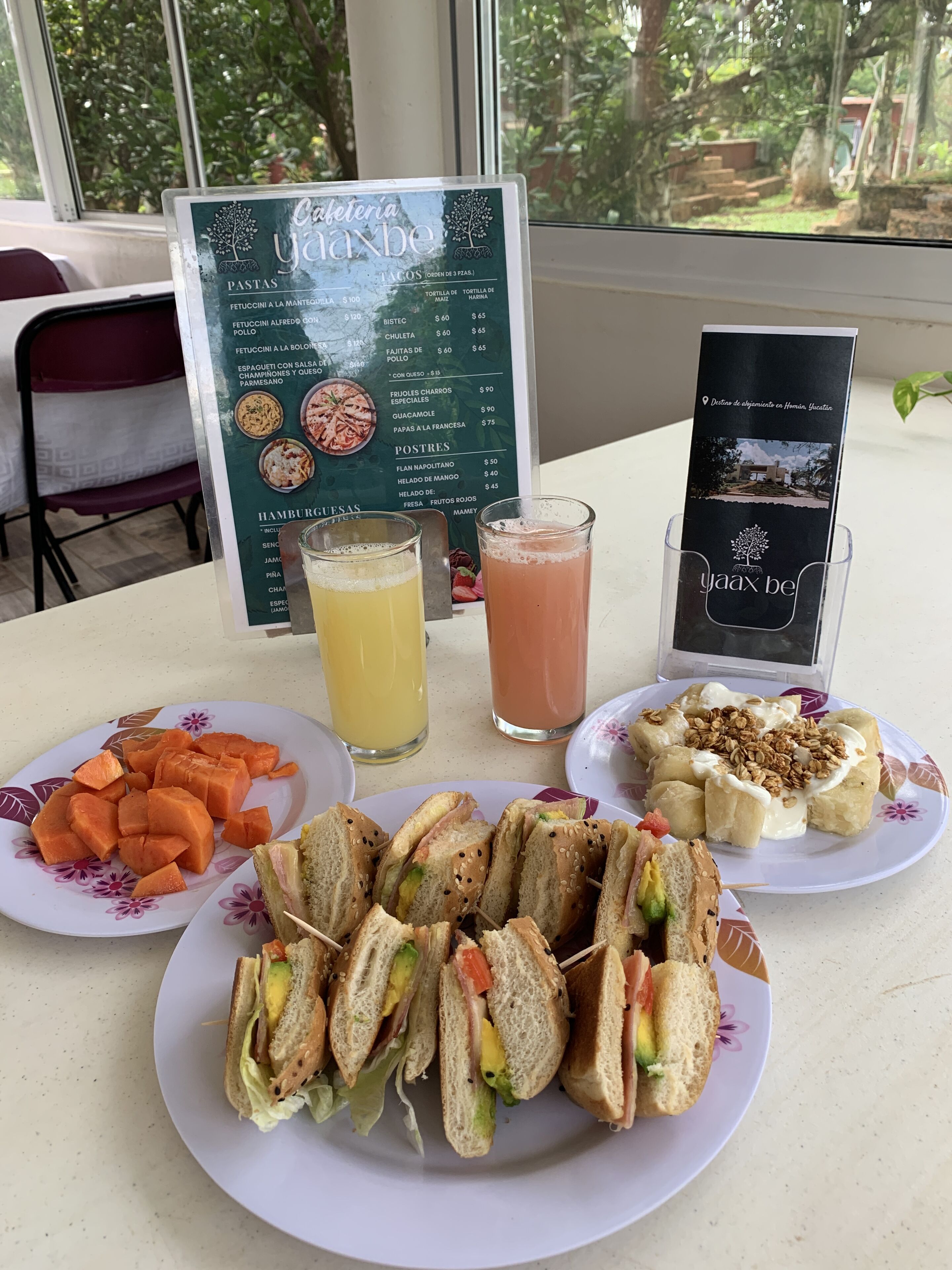 A table with a menu, plates of food, and drinks.