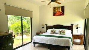 A bedroom with a bed, a desk, a chair, a ceiling fan, and a view of the outdoors. - Quinta Yaaxbe (Homún)