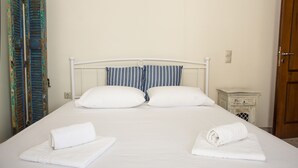 A neatly made bed with white linens and two rolled towels, a striped pillow, and a small bedside table with a lamp. - Christina Apartment 2nd Floor (Kissamos)