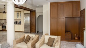 A spacious living area with a sofa set, a wooden wardrobe, and a kitchen in the background. - Christina Apartment 2nd Floor (Kissamos)
