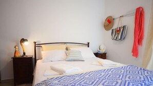 A neatly made bed with a patterned blanket, a bedside lamp, and a small nightstand with a decorative item. - Christina Apartment 1st Floor (Kissamos)