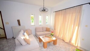 A living room with a beige sofa, a wooden coffee table, and a radiator. - Christina Apartment 1st Floor (Kissamos)