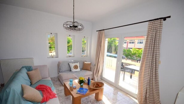 A living room with a sofa, a coffee table, and a view of the outside. - Christina Apartment 1st Floor (Kissamos)