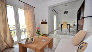 A spacious living area with a wooden coffee table, a sofa, and a dining area with a table and chairs. - Christina Apartment 1st Floor (Kissamos)