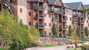 A multi-story hotel with balconies, stone walls, and a paved driveway.