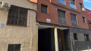 A multi-story building with a red facade, multiple windows, and a visible entrance. - Estancias Mensuales Terrassa (Terrassa)