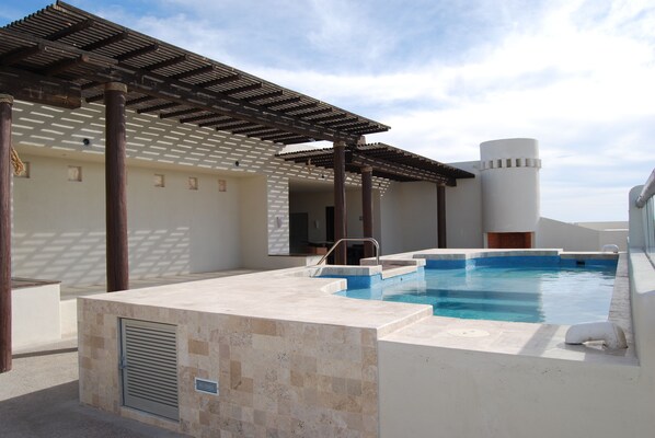 A swimming pool with a pergola and a white cylindrical structure.