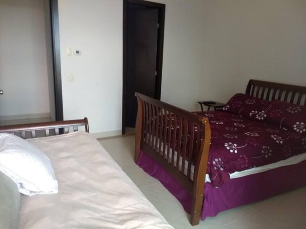 Ein Schlafzimmer mit einem Bett, einem Holzkopfende und einer violetten Tagesdecke.