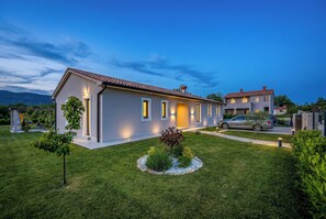 Una casa moderna de dos pisos con un césped bien cuidado y un pequeño jardín.