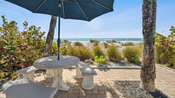 Une terrasse extérieure avec une table et des bancs, donnant sur une plage.