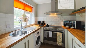 Een kleine keuken met een spoelbak, fornuis, magnetron en oven.