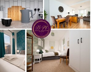 A modern kitchen with a coffee machine, a dining area with a wooden table and chairs, a bedroom with a bed and a nightstand, and a living room with a sofa and a TV. - Heart of the City, Beautiful 3 bed 2 Bath, Sleep 6 (Lincoln)