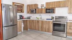 Una cocina moderna con electrodomésticos de acero inoxidable, armarios de madera y suelo de baldosas.