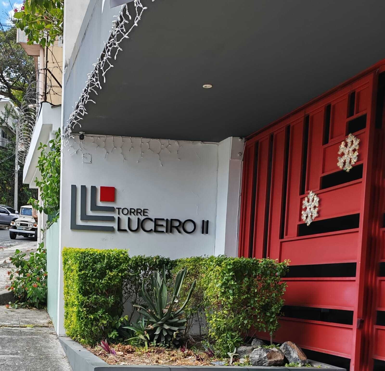 Un edificio con un letrero que dice 'TORRE LUCEIRO II' y una puerta roja con detalles decorativos.