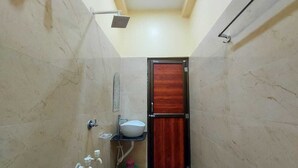 A narrow bathroom with a shower, a sink, and a toilet. - BLUESTONE HOTEL & RESTAURANT (Kanthi)