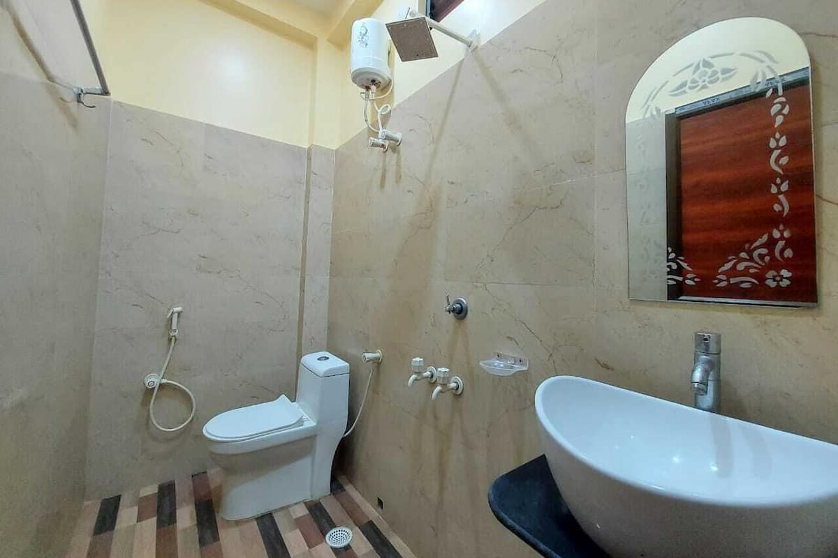 A bathroom with a toilet, bidet, shower, and sink.