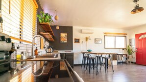 A modern kitchen with a wooden countertop, a sink, and a dining area with bar stools. - Cozy casita on quiet desert hillside with views, fire pit and grill! (Yucca Valley)