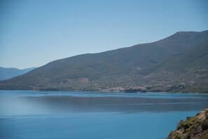 Un paisaje costero con una montaña al fondo y agua tranquila en primer plano.