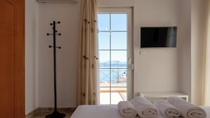 Une chambre d’hôtel avec un lit, une télévision, un porte-manteau et une vue sur la mer.