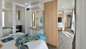 Una camera d'albergo moderna con un letto, un comodino, uno specchio e vista sull'angolo cottura.