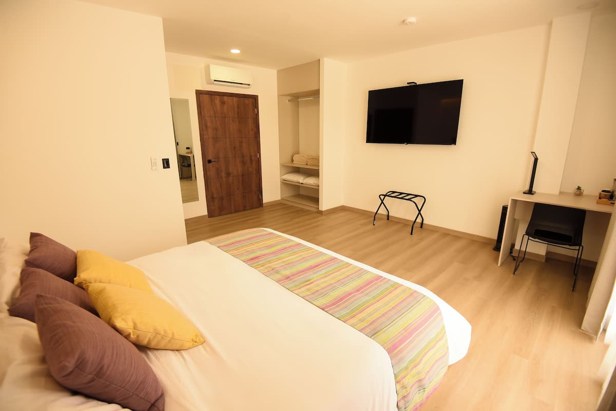 A bedroom with a bed, a desk, and a TV.