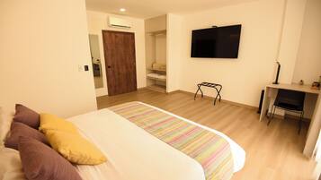 A bedroom with a bed, a desk, and a TV.