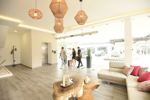 A spacious lobby with a modern design, featuring a wooden coffee table, a sofa with red cushions, and a large window offering a view of the outside. - ELITHE Hotel (La Esperanza)