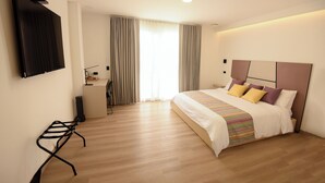 Et moderne hotelværelse med en stor seng, et skrivebord og et tv ophængt på væggen.