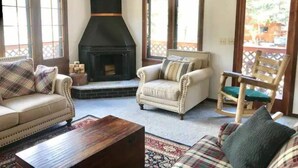 A living room with a fireplace, two sofas, a wooden coffee table, and a chair. - November Riverfront Retreat Near Estes Park and RMNP (Drake)