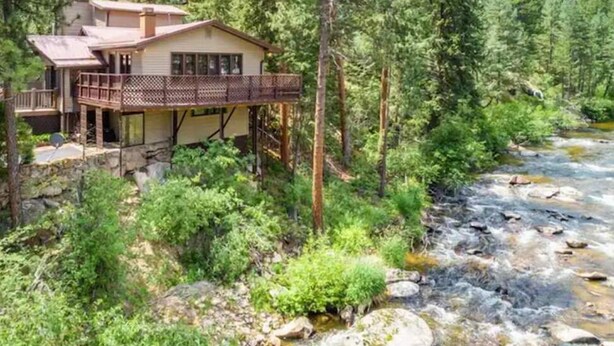 A lodge with a balcony overlooking a river, surrounded by dense forest. - November Riverfront Retreat Near Estes Park and RMNP (Drake)