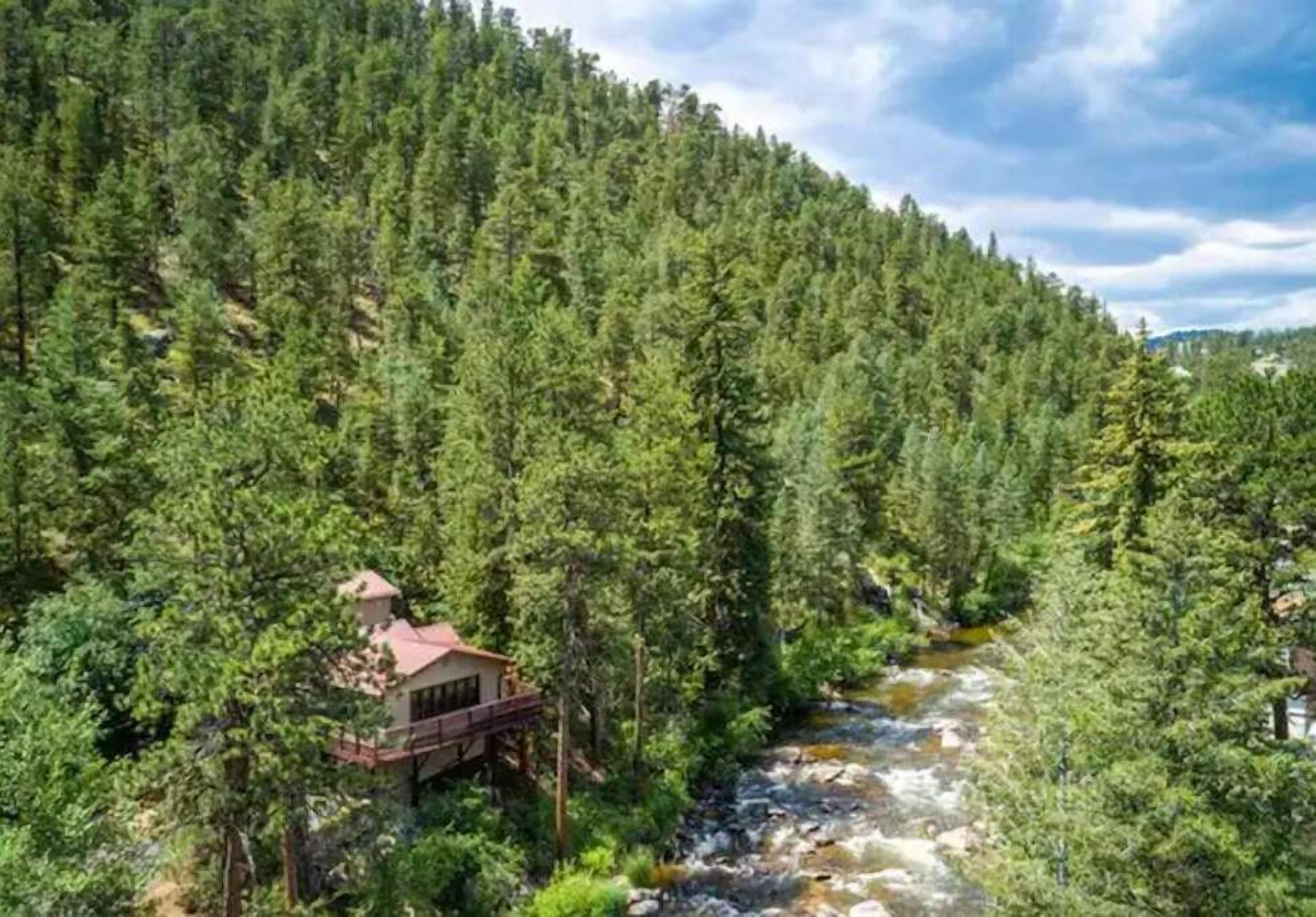 Eine Lodge, umgeben von dichtem Wald und einem Fluss.