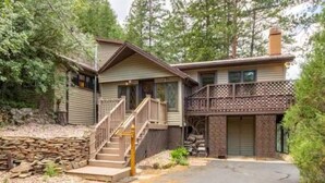 A two-story cabin with a stone foundation, a wooden deck, and a staircase leading to the entrance. - November Riverfront Retreat Near Estes Park and RMNP (Drake)