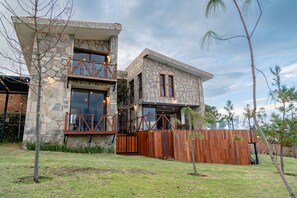 A two-story stone building with large windows and a wooden deck.