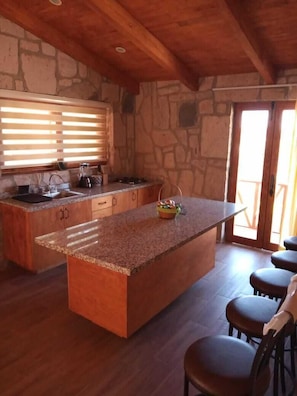A kitchen with a large island, wooden cabinets, and a stone wall.