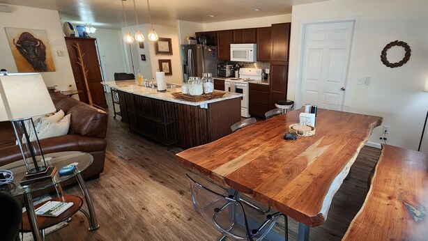 Una cocina moderna con una isla de madera, electrodomésticos de acero inoxidable y una zona de comedor con mesa y sillas de madera.