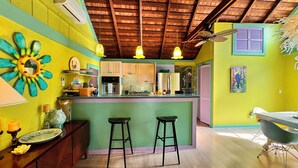 A vibrant kitchen with a wooden ceiling, a bar area with stools, and a dining table with chairs. - Beautiful Old Town 2 bedroom Cottage on a Private Lane (Key West)