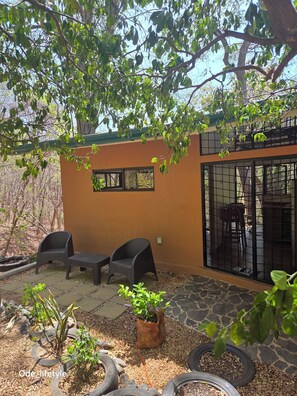 An outdoor patio with a table and chairs, surrounded by potted plants and tire planters.