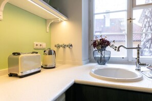 A kitchen with a white countertop, a toaster, a kettle, a sink, and a vase with flowers.