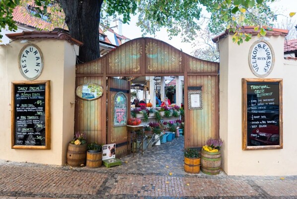 A rustic wooden gate with a signboard listing daily specials and traditional Czech dishes.