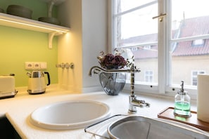 A kitchen with a white sink, a kettle, a vase with flowers, and a window with a view of buildings. - 5-Bedroom Luxury Retreat near Charles Bridge by EasyBNB Premium (Prague)