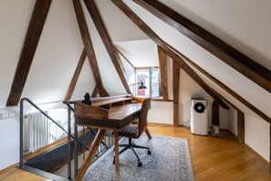 A loft-style room with a wooden desk, chair, and radiator.