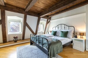 A bedroom with a bed, bedside tables, a window, and wooden beams. - 5-Bedroom Luxury Retreat near Charles Bridge by EasyBNB Premium (Prague)