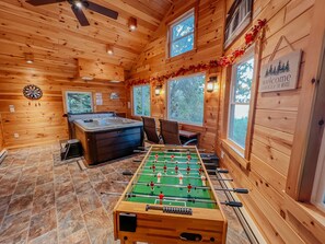 A cozy room with a foosball table, a hot tub, and a dartboard.