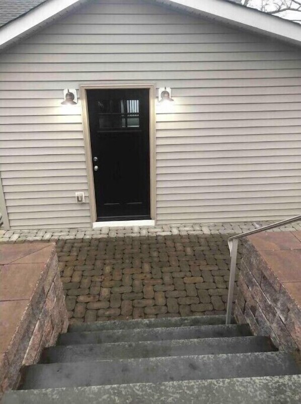 A house with a black front door, a brick staircase leading to the entrance, and a small porch area. - Lakefront Getaway : Mountain & Lakes views (West Milford)