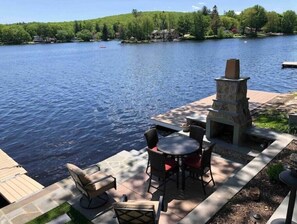 A lakeside patio with outdoor seating and a stone fireplace. - Lakefront Getaway : Mountain & Lakes views (West Milford)