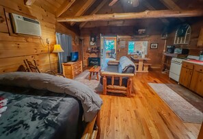 Un chalet confortable avec un intérieur en bois, un lit, un canapé, une table à manger et un coin cuisine.