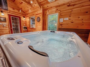 Ein Whirlpool in einer Holzhütte mit Fenster und Dartscheibe an der Wand.