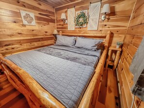 Un dormitorio con paneles de madera, una cama, dos lámparas de pared y un arreglo decorativo.
